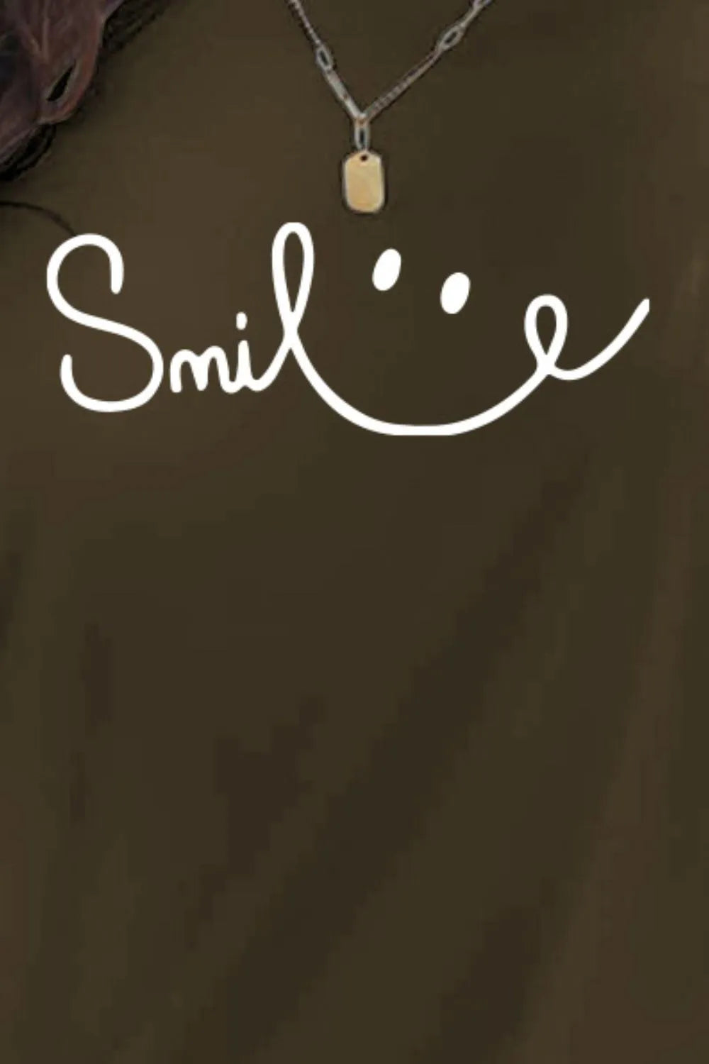 Brown shirt with 'Smile' text and necklace on a dark background