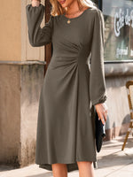 Woman wearing a green dress standing outdoors near a cafe.