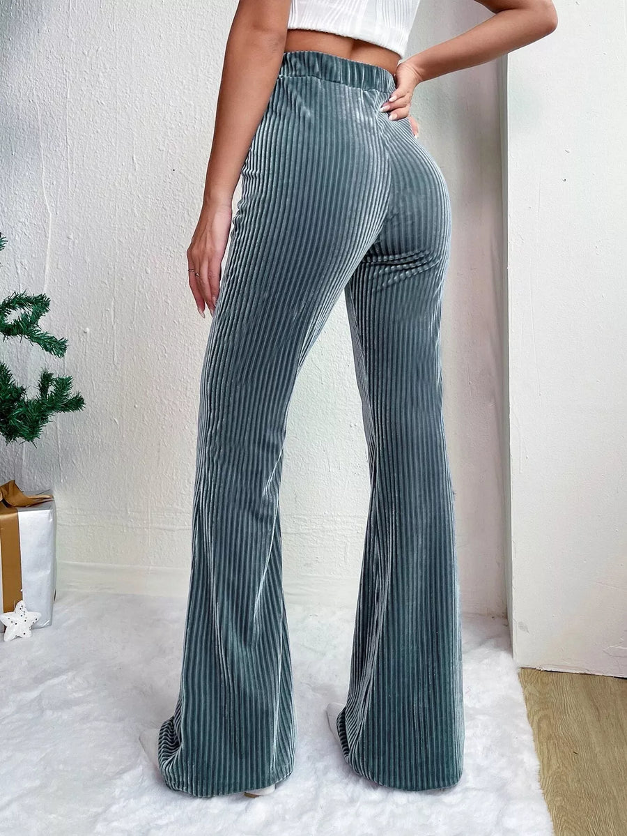 Person wearing green striped flared pants against a white background