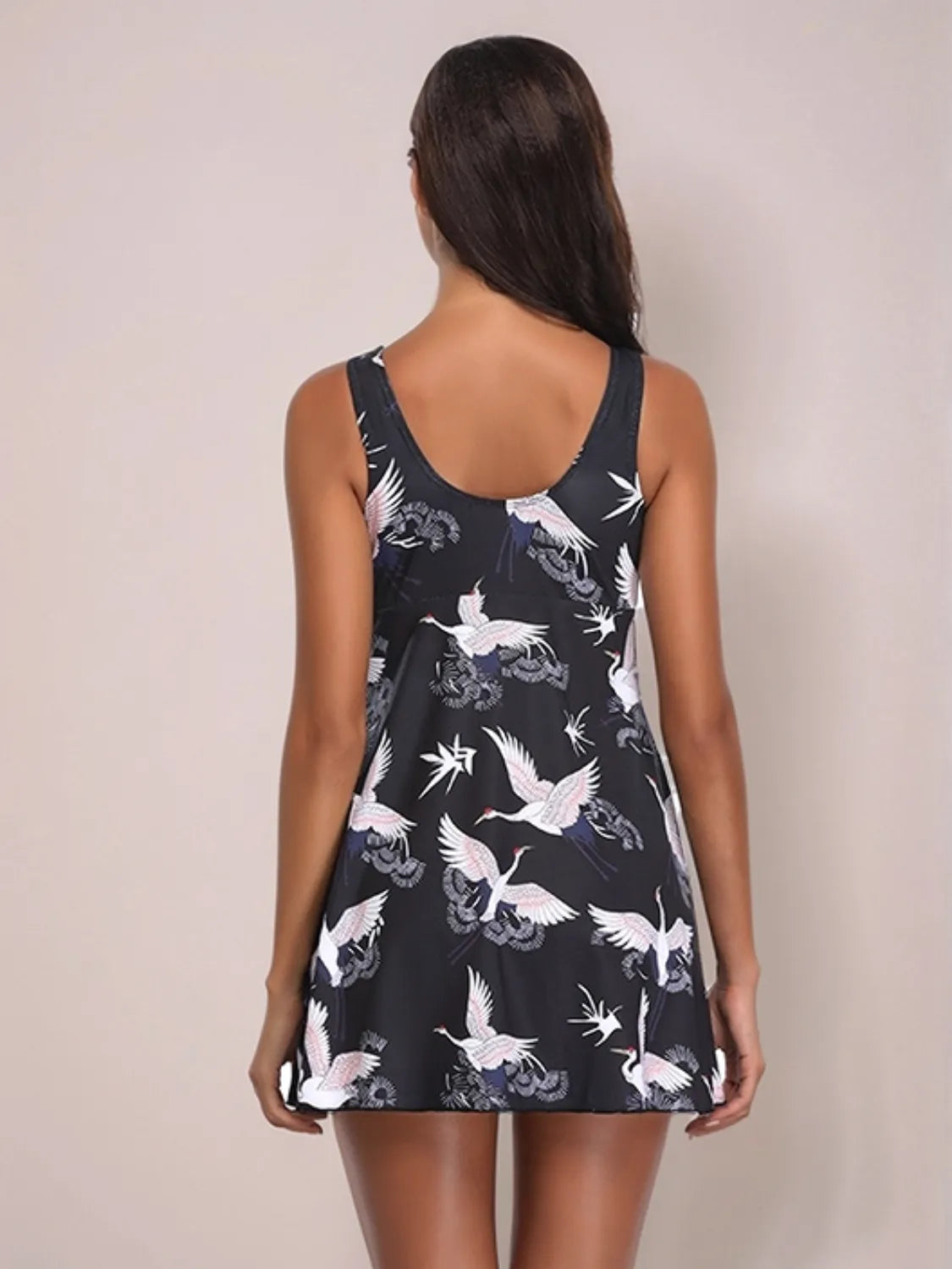 Woman wearing a black dress with white bird pattern on a plain background