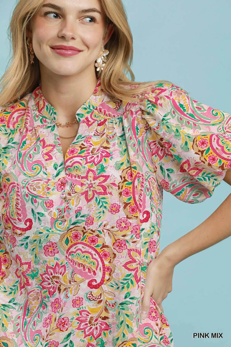 Woman wearing a colorful floral dress against a light blue background