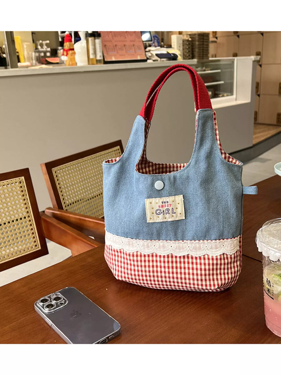 Blue and red checkered bag on a wooden table with a phone and a drink in the foreground.