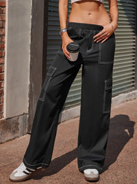 Person wearing black cargo pants holding a coffee cup on a sidewalk.