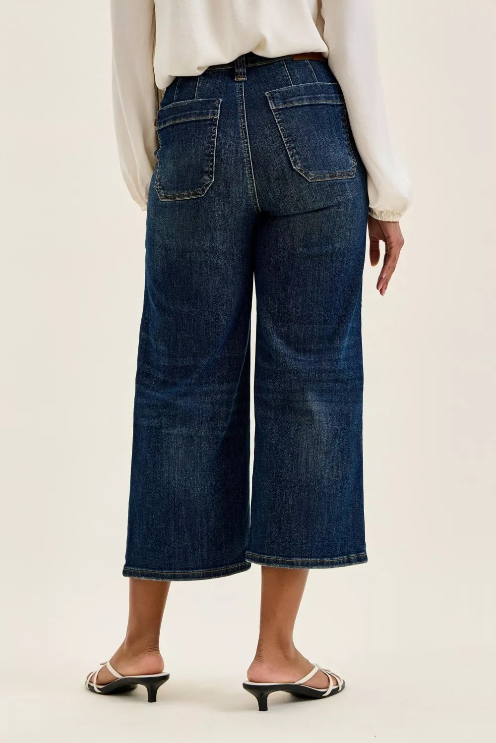 Person wearing dark blue wide-leg jeans on a plain background
