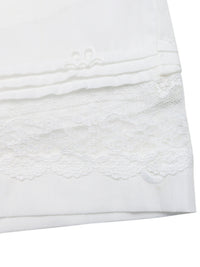 Close-up of a white textured fabric with lace trim on a white background