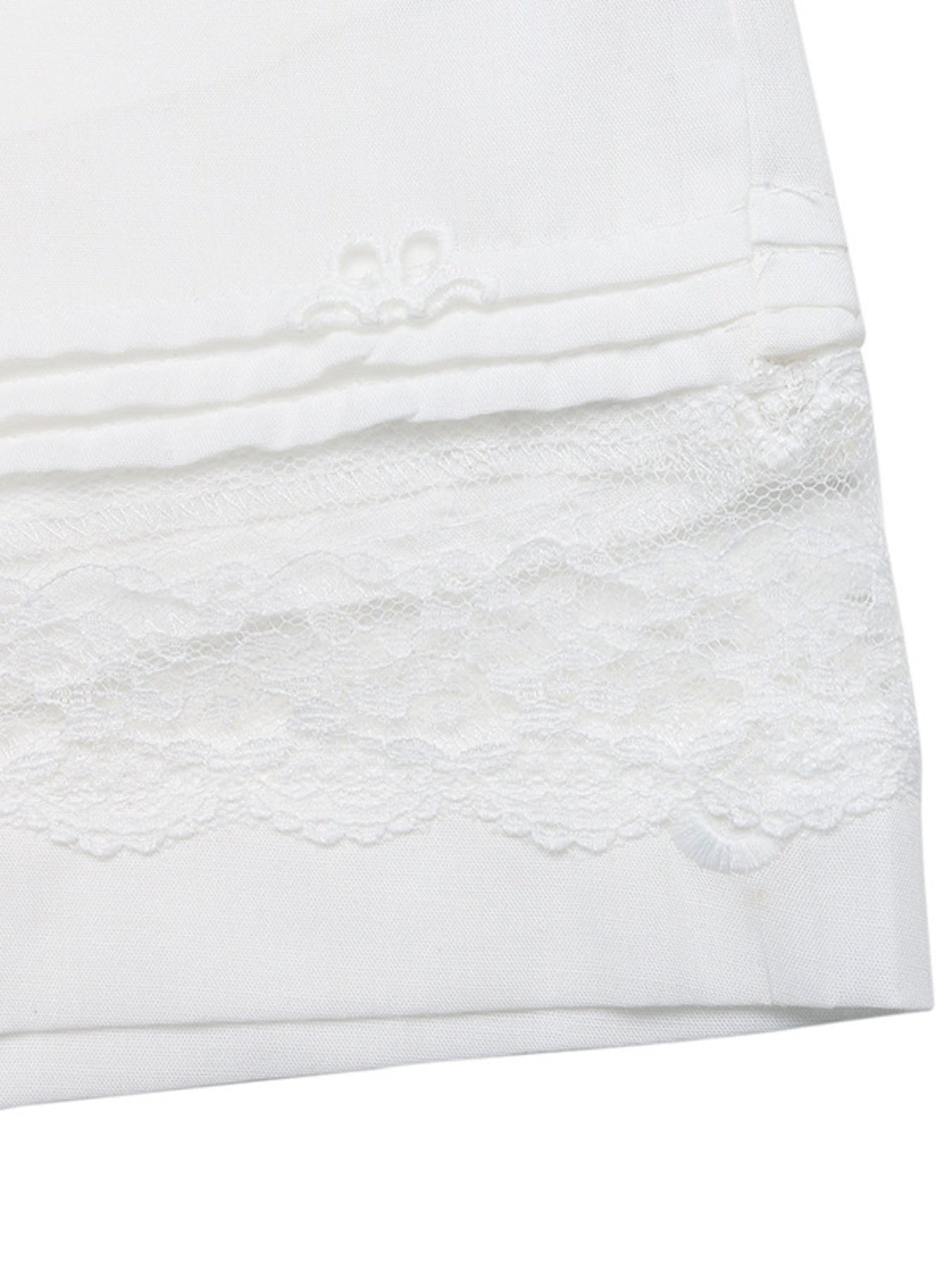 Close-up of a white textured fabric with lace trim on a white background
