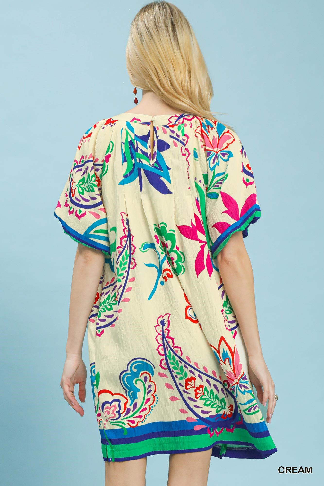 Woman wearing a colorful patterned dress against a light blue background