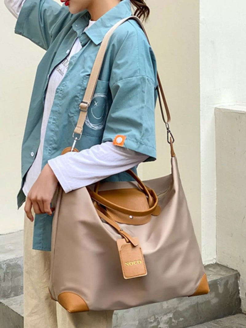 Person holding a beige handbag with brown accents against a neutral background