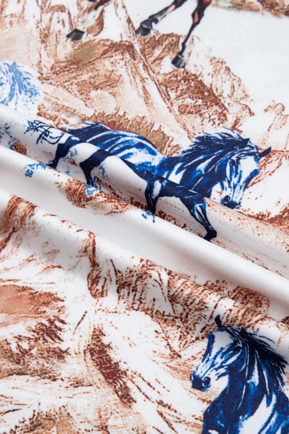 Close-up of fabric with blue and white horse pattern on a brown and beige background