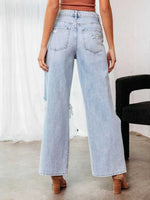 Light blue jeans worn by a person with a white curtain and black chair in the background