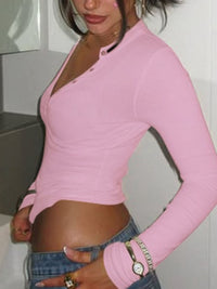 Person wearing a pink long-sleeve top and blue jeans indoors.
