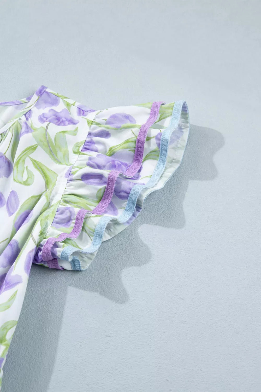 Floral-patterned fabric with purple and green colors on a light gray background