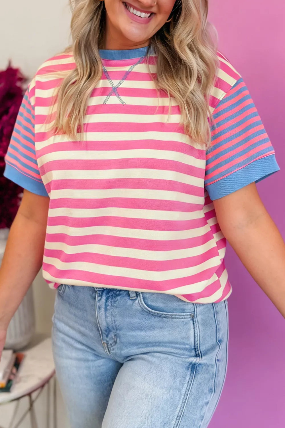 Woman wearing a pink and blue striped shirt with a blurred background