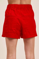 Red shorts worn by a person on a beige background