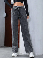 Person wearing high-waisted black jeans with a tie detail on a plain background