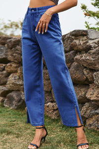 Person wearing blue jeans with a stone wall and grass background