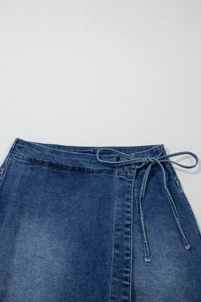 Blue denim skirt with a tie waist on a light gray background