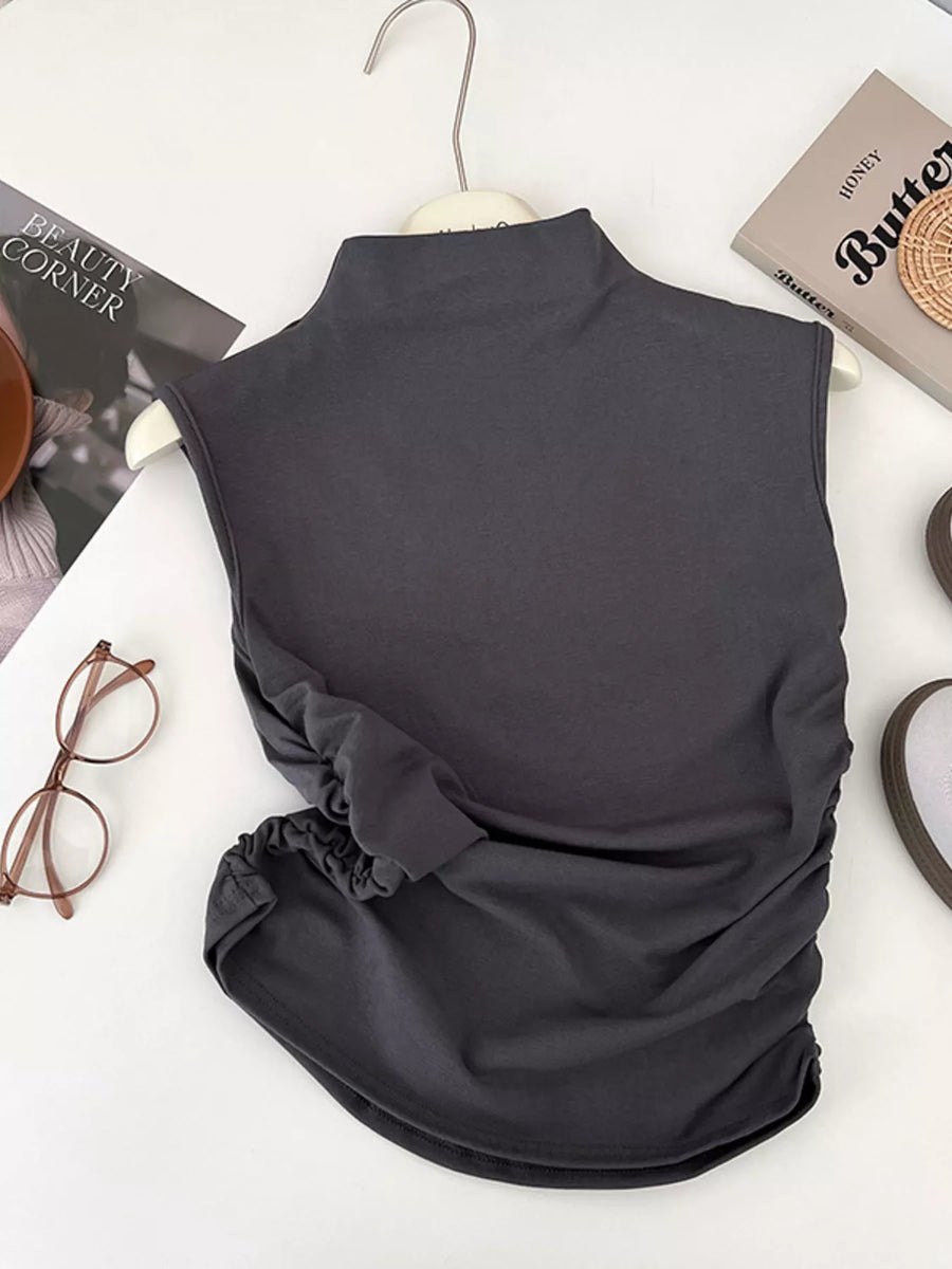 Dark gray sleeveless top on a white surface with books and glasses.