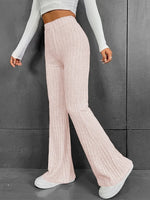 Person wearing light pink ribbed knit pants against a gray background