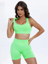 Woman wearing a bright green sports bra and shorts set on a white background