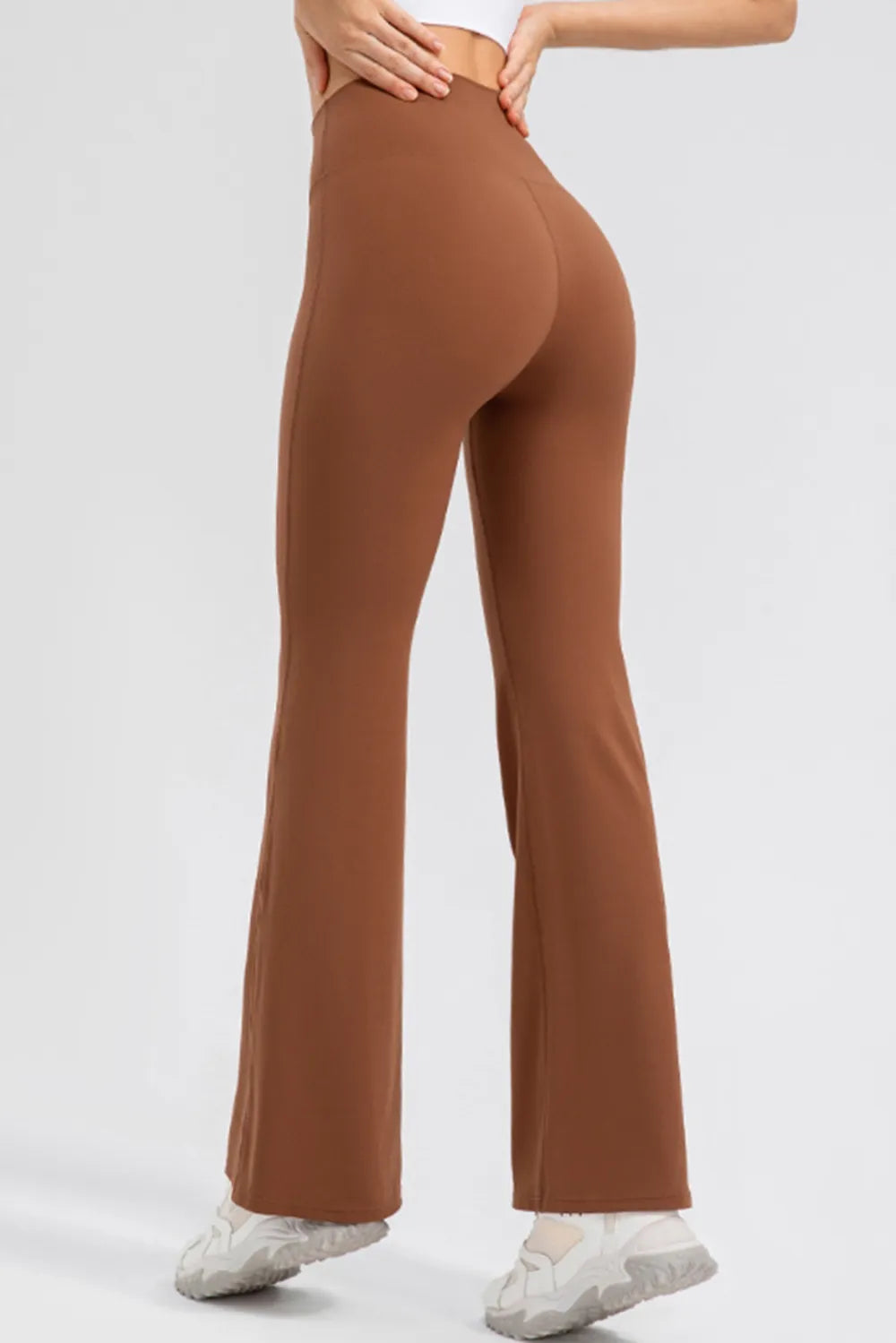 Brown flared pants worn by a person on a white background