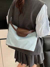Person wearing a light blue bag with brown accents over their shoulder.