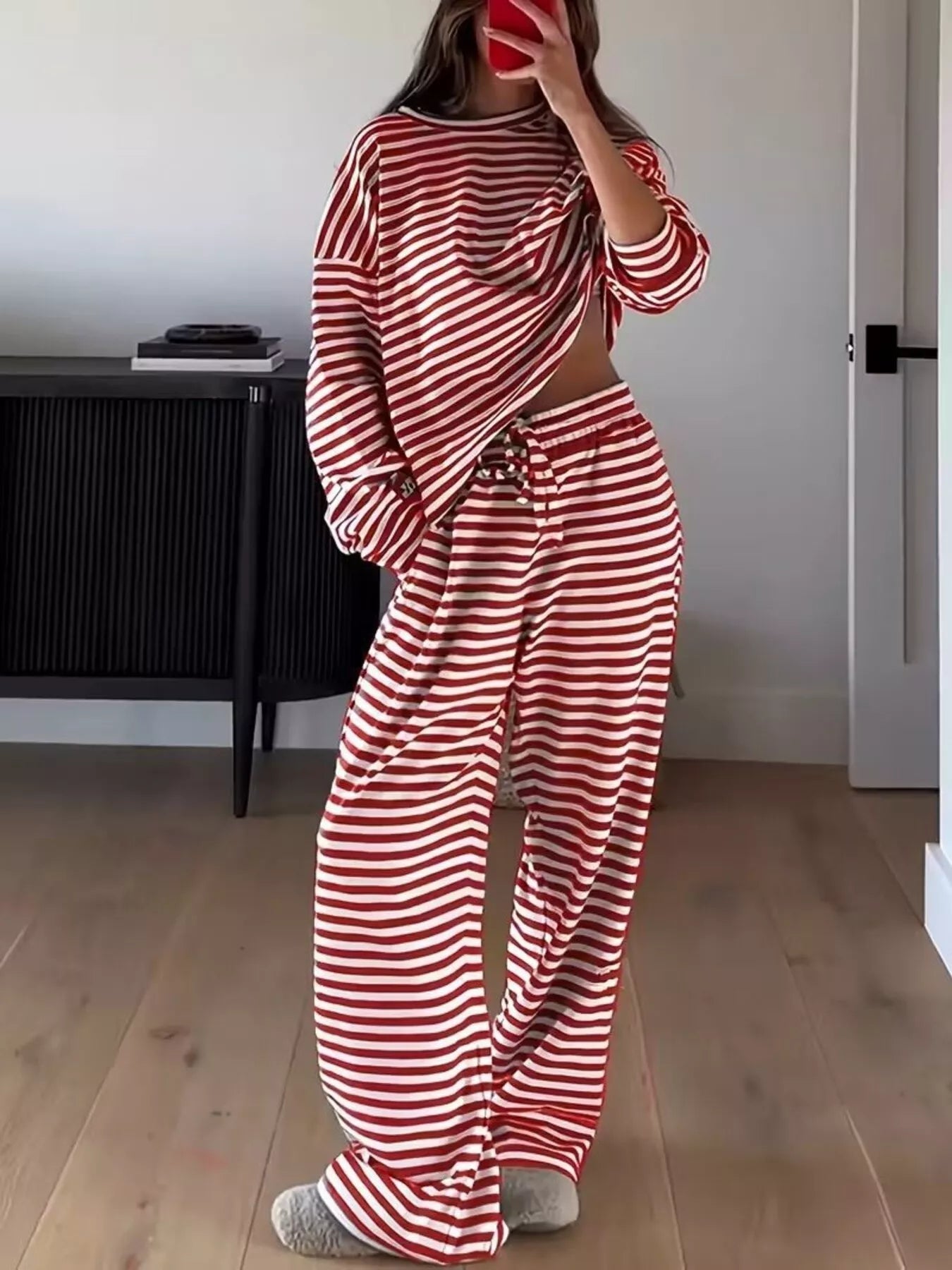 Person wearing a red and white striped outfit in a room with wooden flooring.