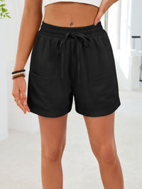 Person wearing black shorts with a white background