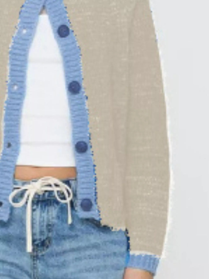 Person wearing a blue cardigan with button details, white shirt, and denim jeans.