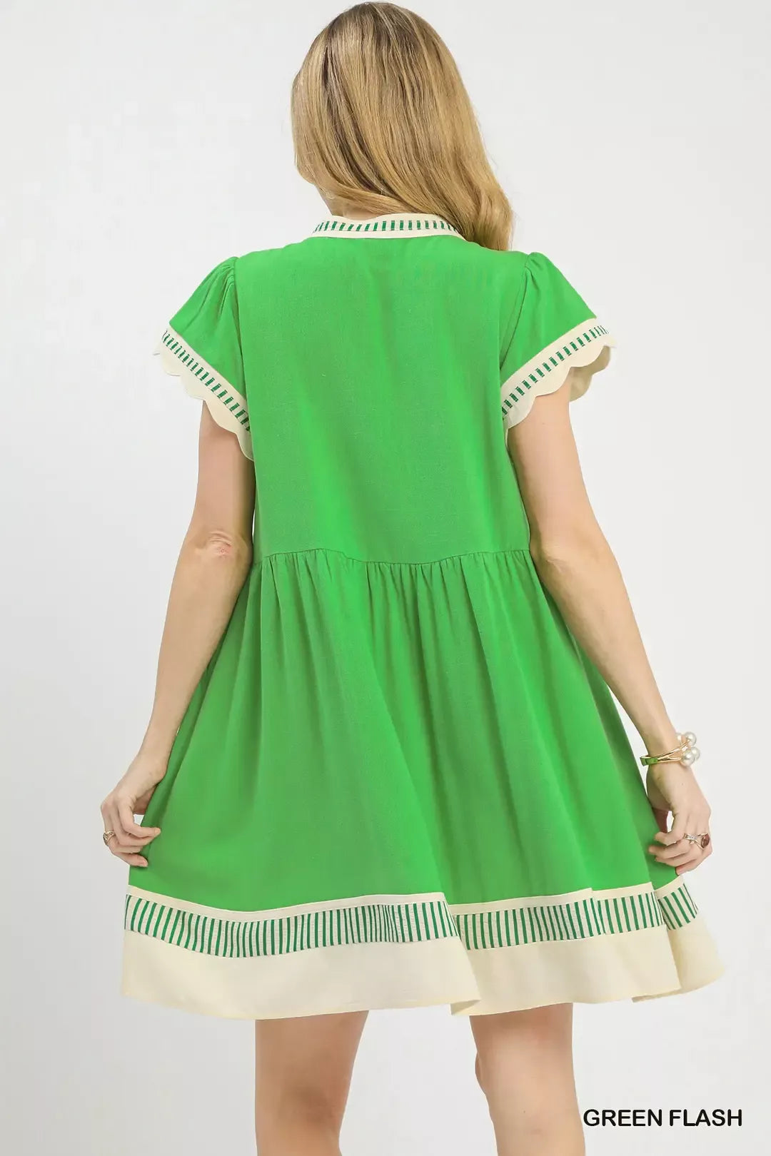 Green dress with white and beige trim worn by a model on a white background