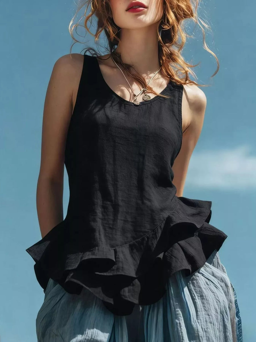 Woman wearing a black sleeveless top with ruffled details against a blue sky.