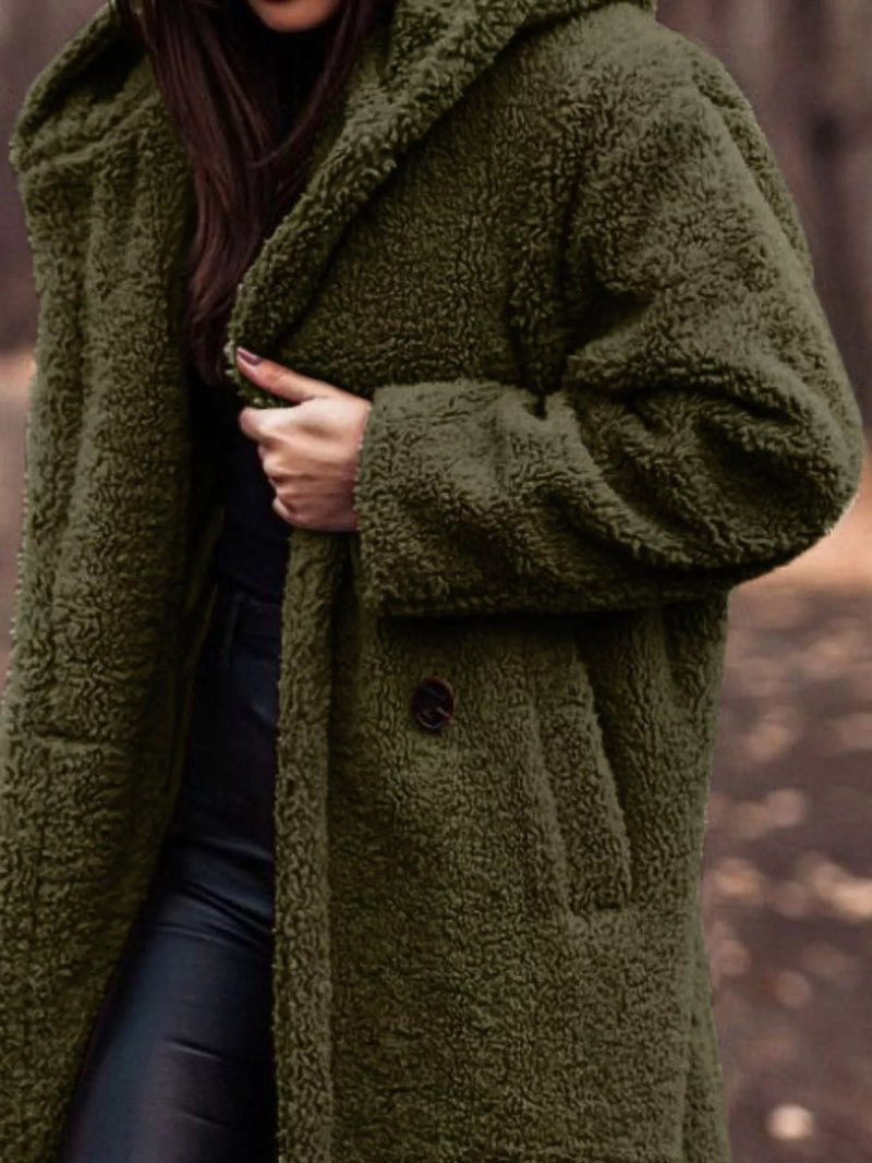 Person wearing a green teddy coat with a blurred background