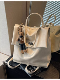 Beige handbag with a keychain on a black surface