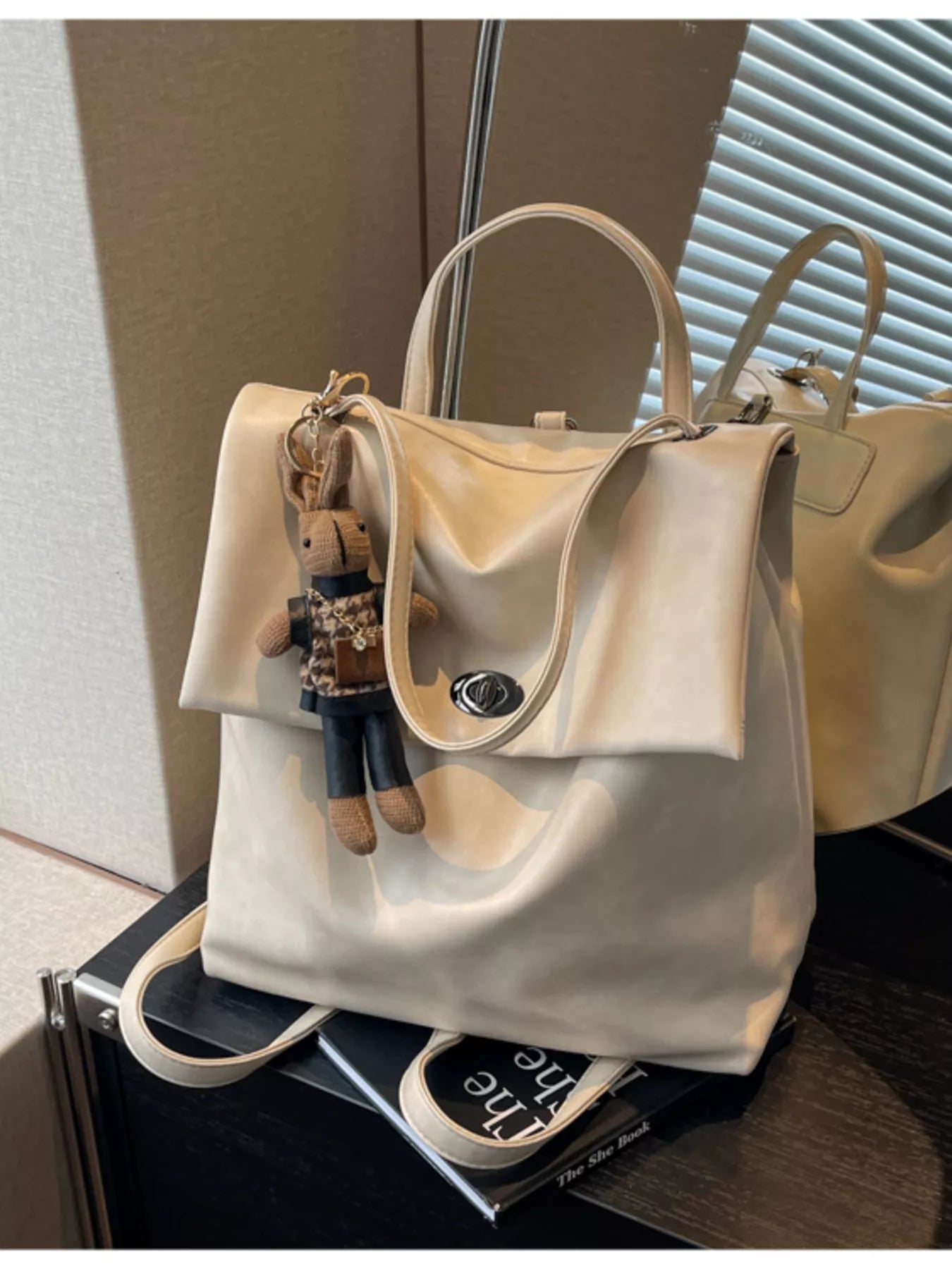 Beige handbag with a keychain on a black surface
