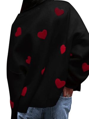 Black hoodie with red heart patterns worn by a person on a white background