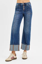 Blue jeans with a button fly worn by a person on a white background