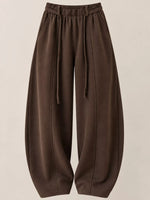 A pair of dark brown wide-leg sweatpants with an elastic drawstring waist, displayed against a solid light beige background.