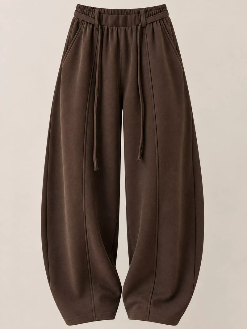 A pair of dark brown wide-leg sweatpants with an elastic drawstring waist, displayed against a solid light beige background.