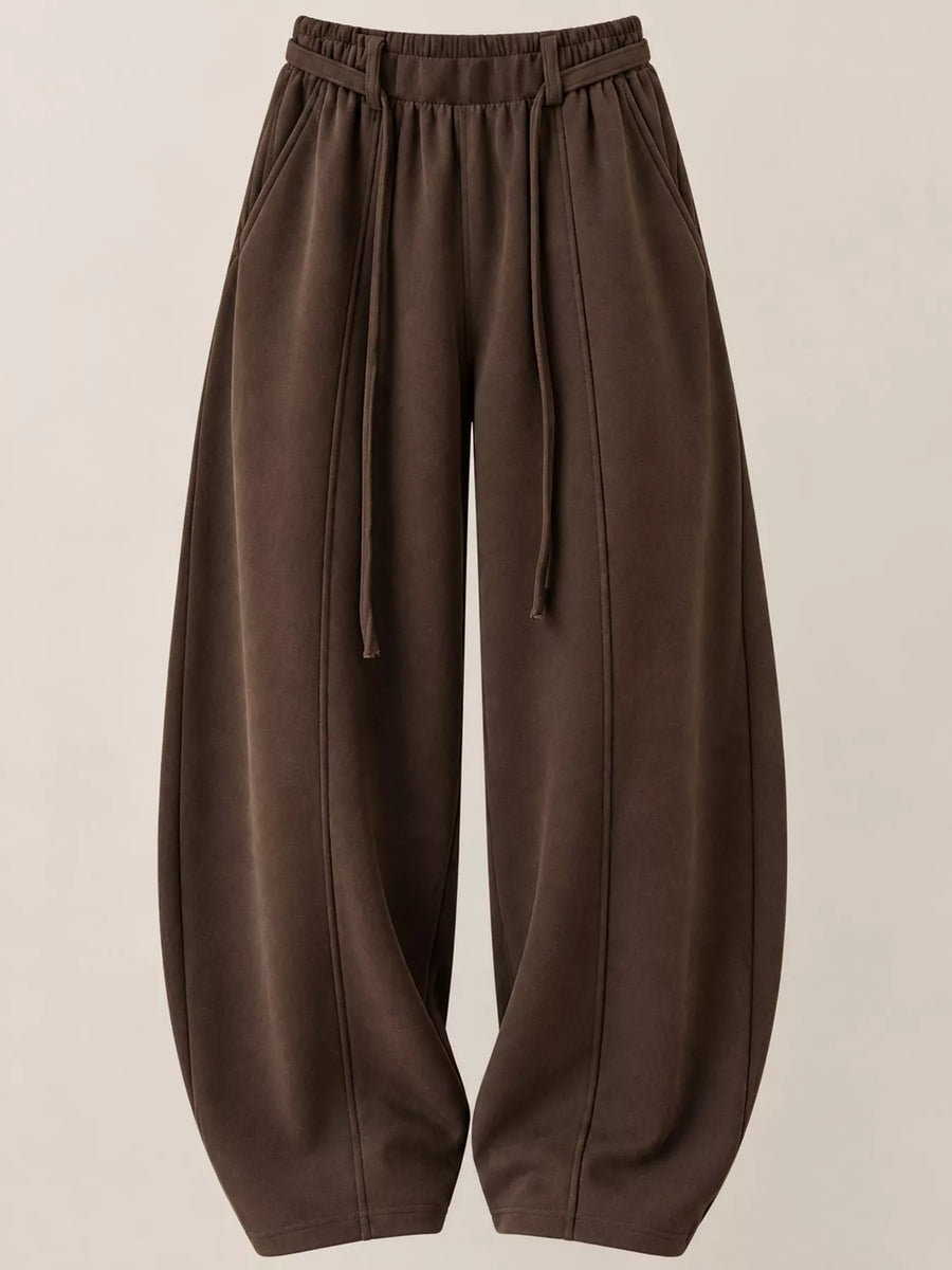 A pair of dark brown wide-leg sweatpants with an elastic drawstring waist, displayed against a solid light beige background.