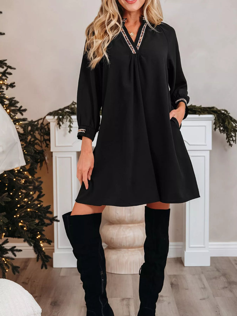 Woman wearing a black dress with long sleeves and over-the-knee boots in a festive indoor setting.