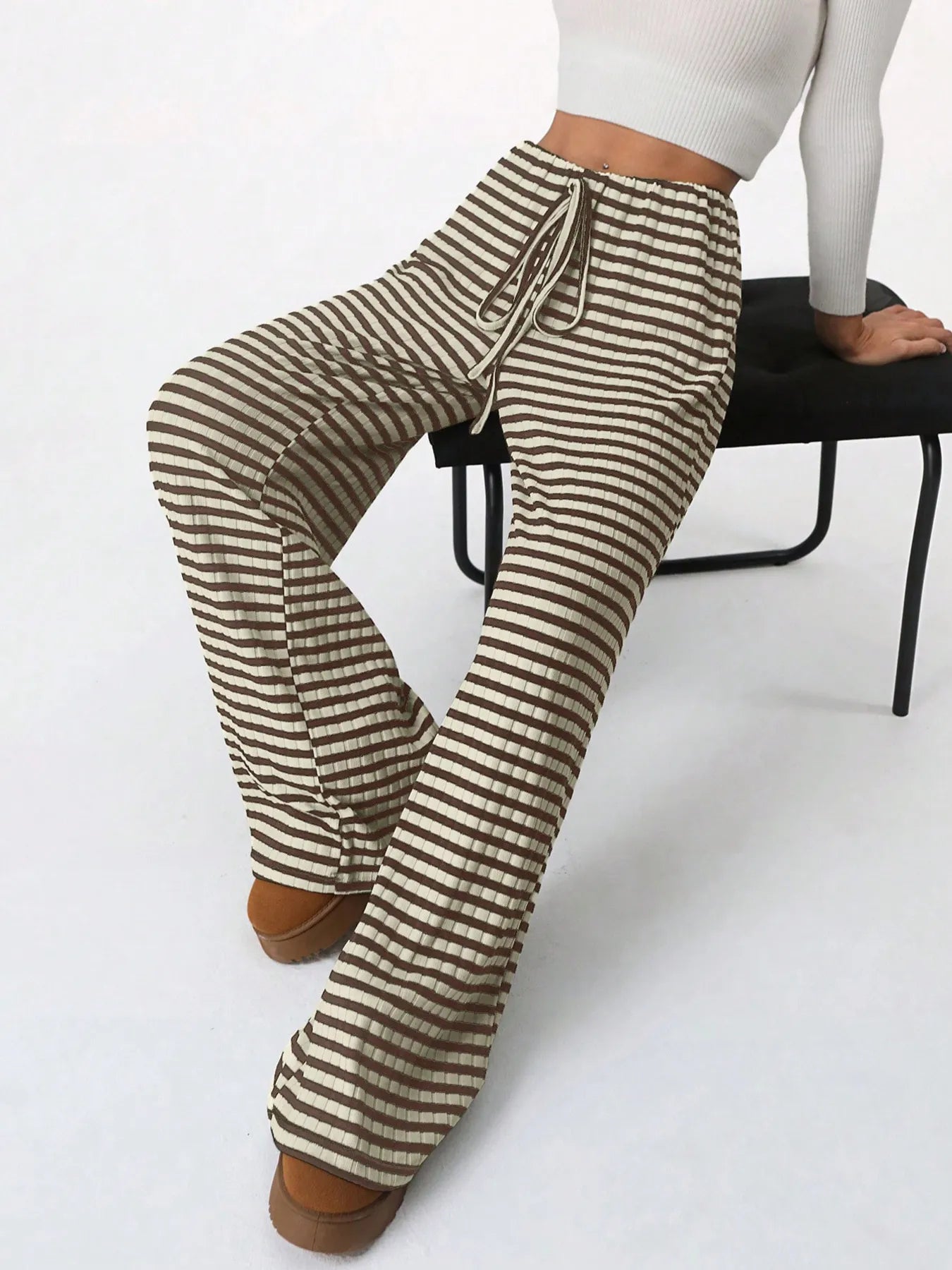 Striped pants worn by a person sitting on a chair with a white background