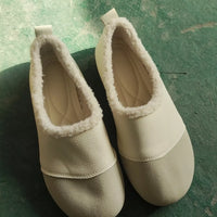 Pair of beige slippers on a green surface
