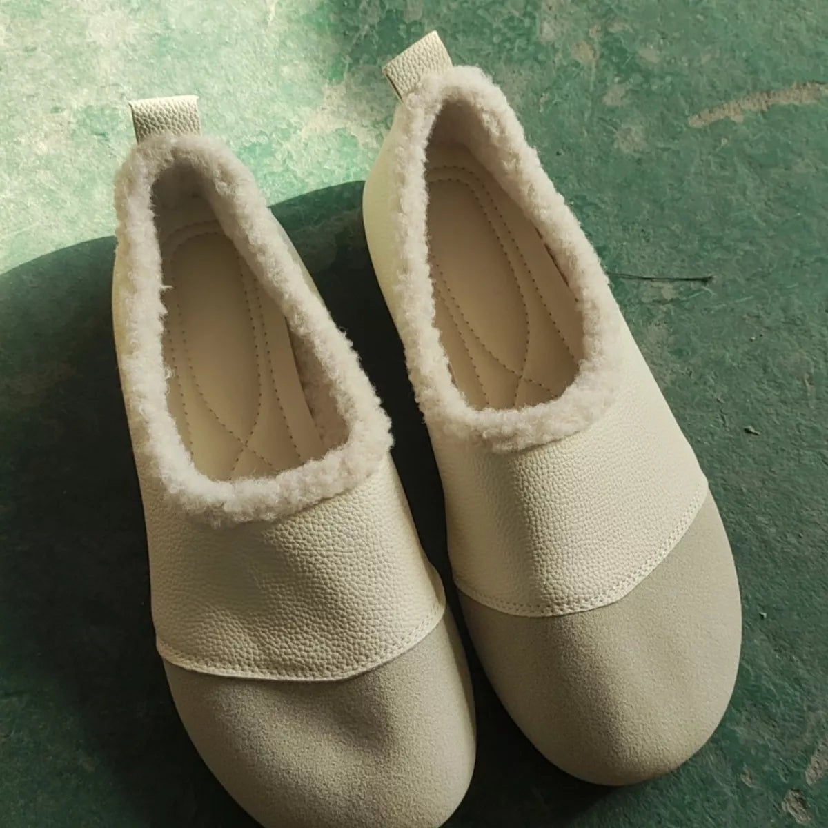 Pair of beige slippers on a green surface