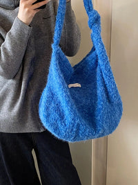 Person holding a blue textured handbag against a neutral background