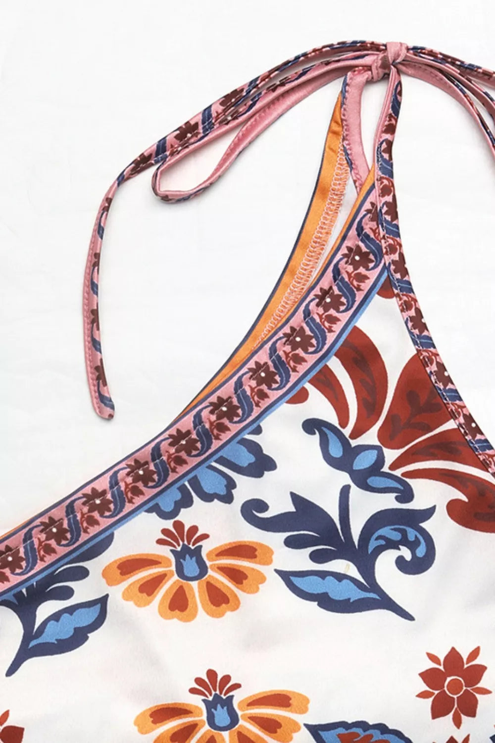 Triangular bikini top with colorful floral pattern on a white background