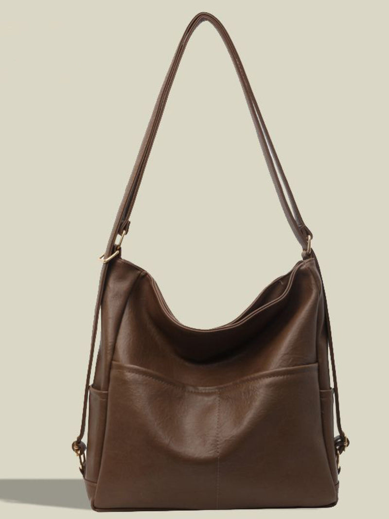Brown leather handbag with a shoulder strap on a beige background