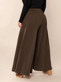 Brown wide-leg pants worn by a person on a beige background