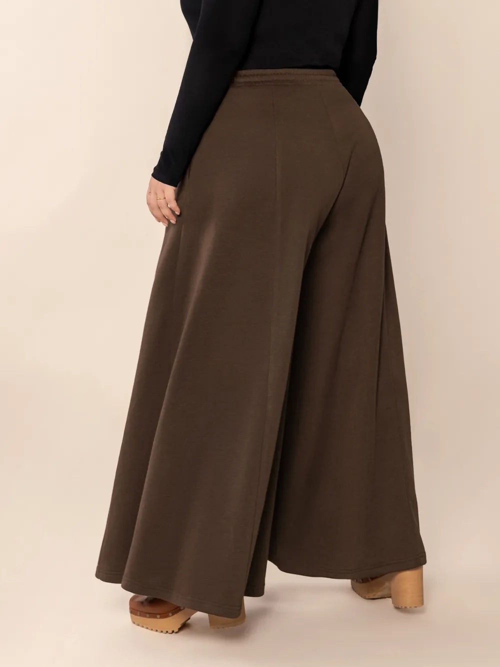 Brown wide-leg pants worn by a person on a beige background