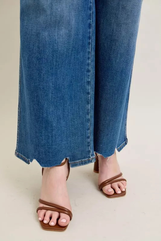 Person wearing blue jeans and brown sandals on a neutral background