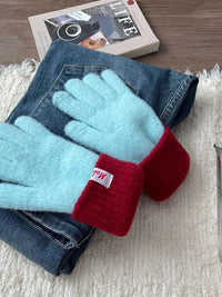 Pair of light blue gloves with red cuffs on a denim jacket and newspaper background